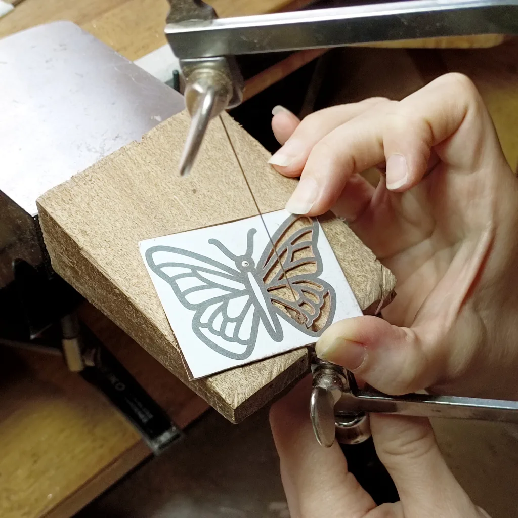 Jewelry making for beginners – student practicing on a copper sheet during a pendant-making class.
